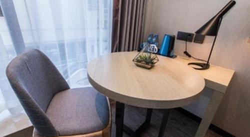 a desk with a chair and a table with a lamp at Echarm Hotel Hefei West Qilitang Metro Station in Hefei