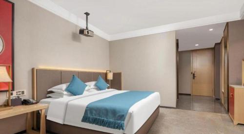 a bedroom with a large bed with blue pillows at E-Cheng Hotel Yangjiang Baili Plaza in Yangjiang