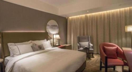 a hotel room with a large bed and a chair at E-Cheng Hotel Yangjiang Baili Plaza in Yangjiang