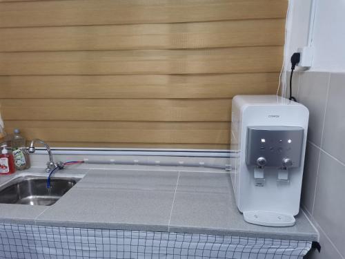 a kitchen counter with a sink and a paper towel dispenser at KhaiLa Emerald Apartment Cameron Highlands in Brinchang