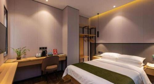 a bedroom with a bed and a desk with a computer at Green Tree Inn Express Fuzhou Three Lanes and Seven Alleys Nanmendou Metro Station in Fuzhou