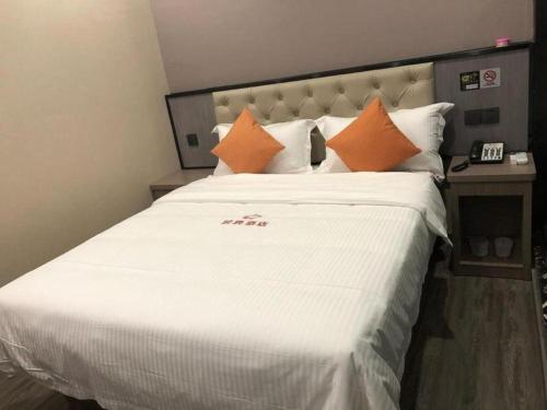 a large white bed with orange pillows in a room at Shell Hotel Shanghai Jinshan Wanda Plaza in Nanhui