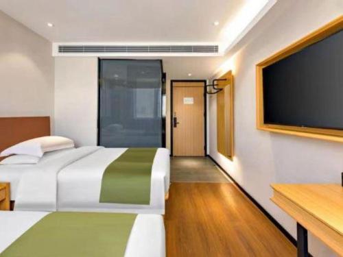 a bedroom with a large bed and a flat screen tv at GreenTree Inn Express Datong High-Speed Railway Station Old City Wall in Datong