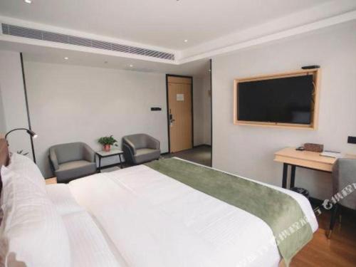 a bedroom with a bed and a desk and a television at GreenTree Inn Express Datong High-Speed Railway Station Old City Wall in Datong