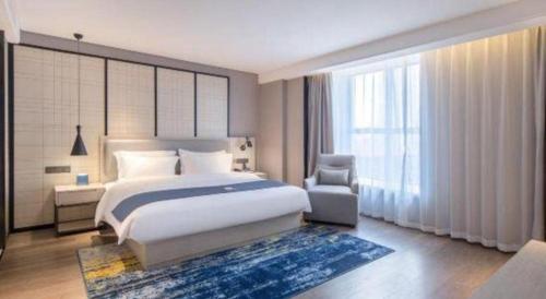 a bedroom with a bed and a chair and a window at Echarm Hotel Nanning the MixC Dongmeng Business District in Nanning