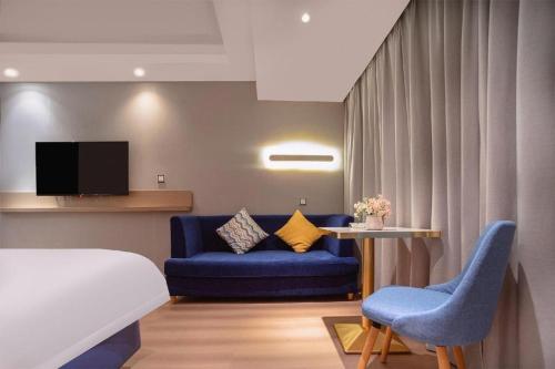 a hotel room with a blue couch and a tv at Borrman Hotel Liuzhou High-Speed Railway Station in Liuzhou