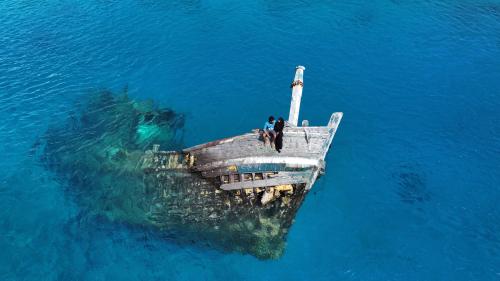 two people sitting on a dock in the water at Uhoo's Lavish Oasis in Felidhoo