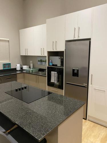 a kitchen with white cabinets and a stainless steel refrigerator at Sunset at 30 Nivica Luxury Apartment in Langebaan