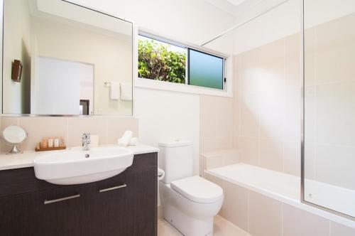 a bathroom with a sink and a toilet and a tub at Jalun Bayun The Sea House in Newell Beach