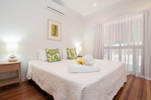 a white bedroom with a large bed with flowers on it at Jalun Bayun The Sea House in Newell Beach