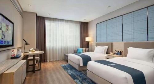 a hotel room with two beds and a television at Echarm Hotel Changsha Wuyi Square Xiangya Affiliated 1st Provincial Maternity and Child in Changsha