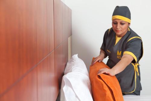 a woman standing next to a bed holding a blanket at Hotel Finlandia in Quito