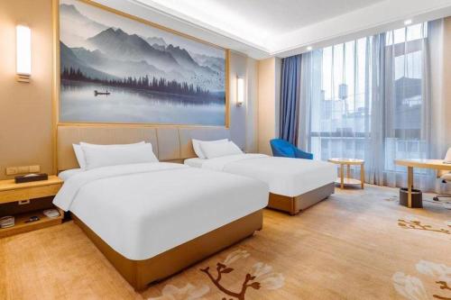 a hotel room with two beds and a large window at Vienna Hotel Baoshan Yongchang Road in Baoshan