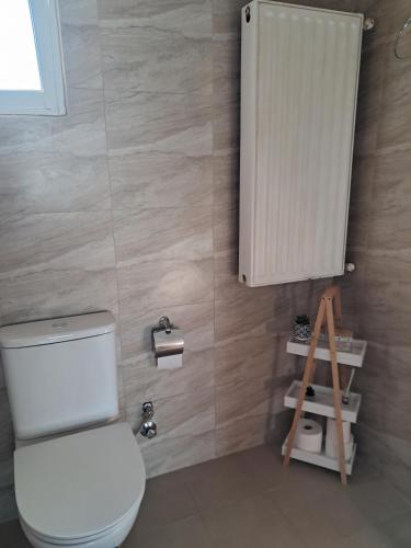 a bathroom with a toilet and a small cabinet at Chris Apartment in Mélissa