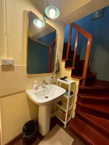 a bathroom with a sink and a mirror and stairs at Hansa Heritage home in Khao San in Bangkok