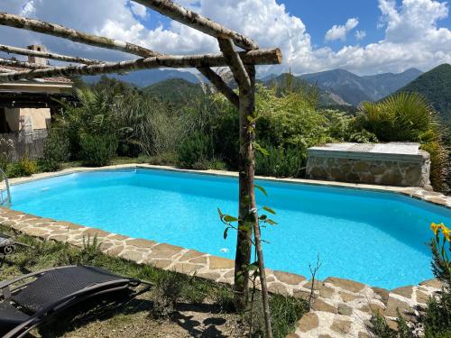 une piscine bleue avec des montagnes en arrière-plan dans l'établissement Love Room Villa Charlene, à Massoins