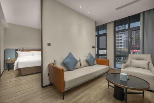 a living room with a couch and a bed at Echarm Hotel Changsha Huanghua Airport in Changsha