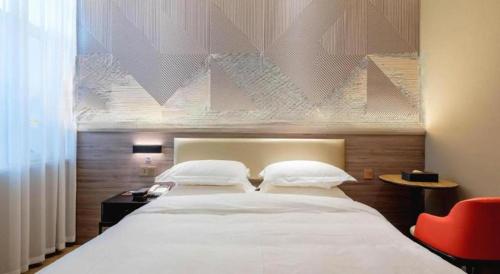 a bedroom with a large white bed and a red chair at Borrman Hotel Korla Peacock River in Korla