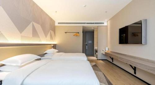 a bedroom with two beds and a flat screen tv at Borrman Hotel Korla Peacock River in Korla