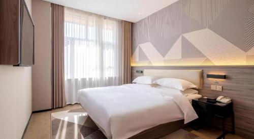 a bedroom with a large white bed and a window at Borrman Hotel Korla Peacock River in Korla