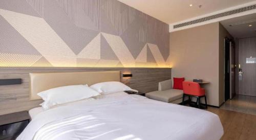 a bedroom with a large white bed and a red chair at Borrman Hotel Korla Peacock River in Korla