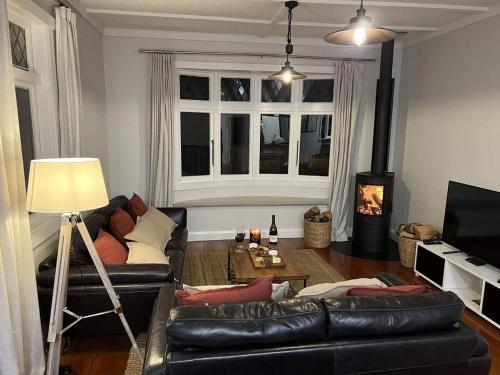 a living room with a black leather couch and a fireplace at Sackville Retreat in Martinborough 