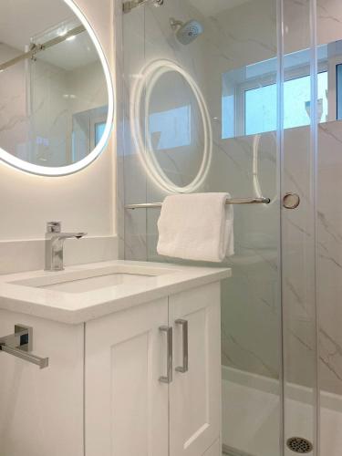 a white bathroom with a sink and a shower at A Beautiful, cozy second floor room for staying in Vancouver