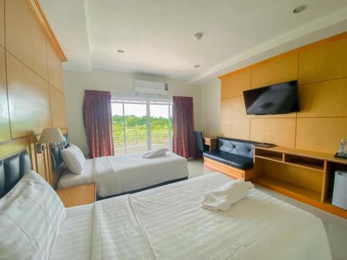 a hotel room with two beds and a flat screen tv at Siamtara Palace Hotel in Maha Sarakham
