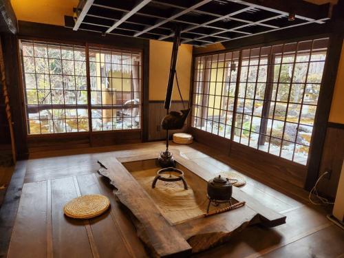 a room with a table in a room with windows at Miyama Resort Kayabuki-tei - Matsuba's Inn in Nantan city