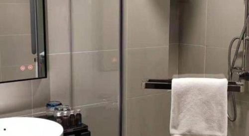 a bathroom with a shower with a sink and a towel at City Comfort Inn Hotel Wuhan Optics Valley Square Metro Station Zhongnan Minzu University in Wuhan
