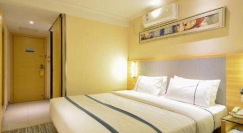 a hotel room with a large bed with white pillows at City Comfort Inn Hotel Wuhan Optics Valley Square Metro Station Zhongnan Minzu University in Wuhan