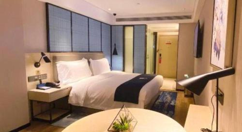 a bedroom with a bed and a table and a lamp at Echarm Hotel Shenzhen World Exhibition and Convention Center in Shenzhen