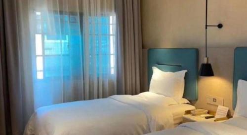 a bedroom with two white beds and a window at ZMAX Hotels Shenzhen Lianhuacun Metro Station in Shenzhen