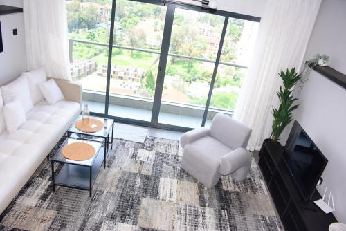 a living room with a white couch and a chair at 2BR WiFi pool gym free breakfast Westlands nairobi in Nairobi