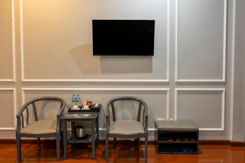 two chairs and a table with a tv on a wall at Clover Hanoi Hotel - City Center in Hanoi