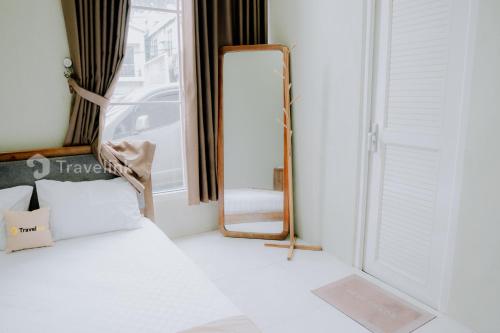 - une chambre avec un miroir, un lit et une fenêtre dans l'établissement Dieng Top Syariah By Travelink, à Diyeng