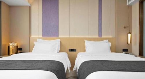 two beds sitting next to each other in a room at Lavande Hotel Guangzhou Quzhuang Metro Station in Guangzhou