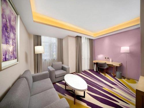 a hotel room with a couch and a table and chairs at Lavande Hotel Changchun Gaoxin Jilin University in Changchun