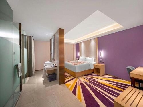 a bedroom with a bed and a purple wall at Lavande Hotel Changchun Gaoxin Jilin University in Changchun