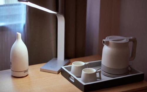 a tea kettle and cups on a table with a lamp at Lavande Hotel Changchun Gaoxin Jilin University in Changchun