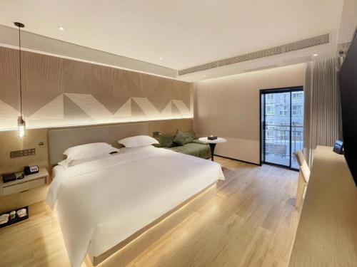a bedroom with a large white bed and a couch at Borrman Hotel Chongqing Bishan Central Street in Chongqing