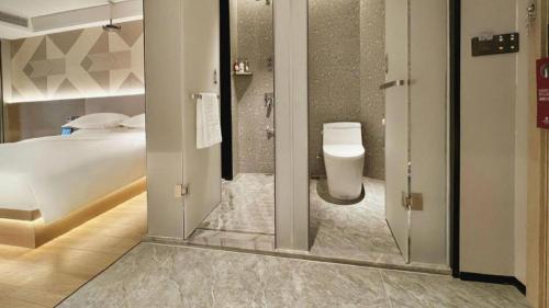 a bathroom with a bed and a toilet in a room at Borrman Hotel Chongqing Bishan Central Street in Chongqing