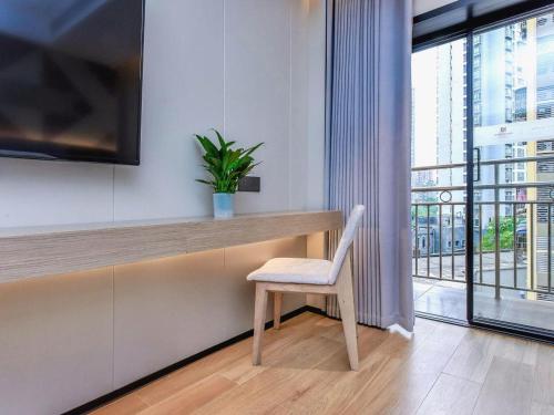 a desk with a chair in a room with a window at Borrman Hotel Chongqing Bishan Central Street in Chongqing