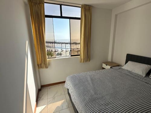 a bedroom with a bed and a large window at Departamento con Vista al Mar 1er Fila in Pimentel