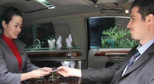 a man and a woman in a car looking at their cell phones at Xiamen Jingmin Central Hotel in Xiamen