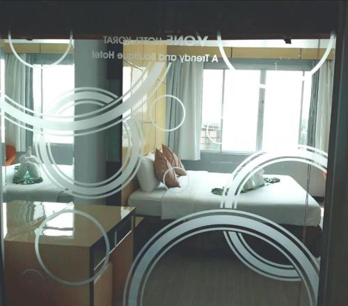 a room with a bed and a table and windows at V-One Hotel Korat in Nakhon Ratchasima