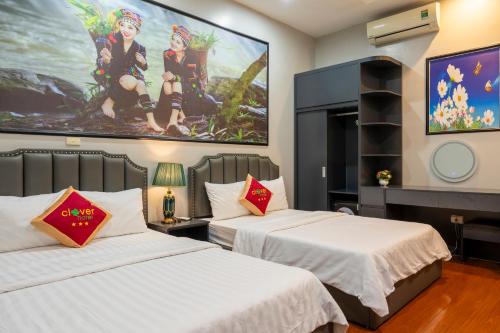 two beds in a room with a painting on the wall at Clover Hanoi Hotel - City Center in Hanoi