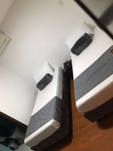 two beds with black and white sheets and pillows at Hotel Castellon Plaza Pereira in Pereira