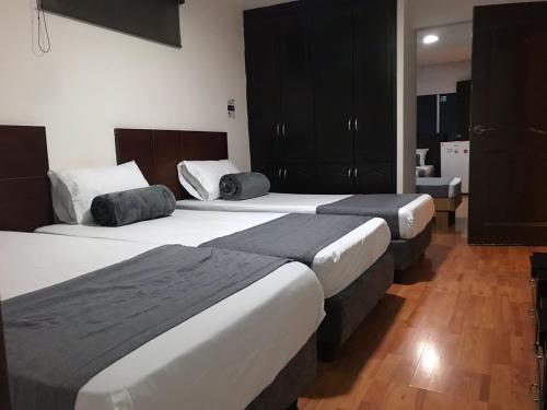 two beds in a hotel room with wooden floors at Hotel Castellon Plaza Pereira in Pereira