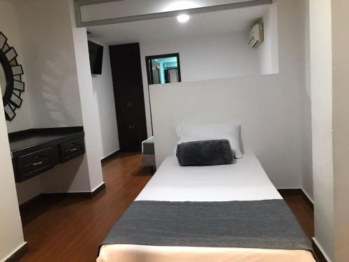 a small bedroom with a bed and a mirror at Hotel Castellon Plaza Pereira in Pereira